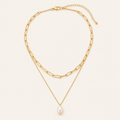 Gold layered pearl necklace on a warm cream background