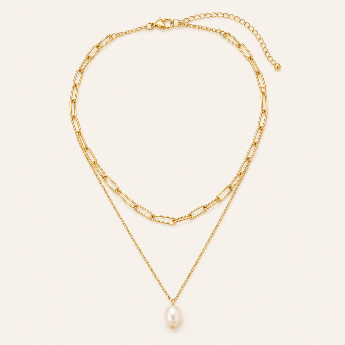 Gold layered pearl necklace on a warm cream background