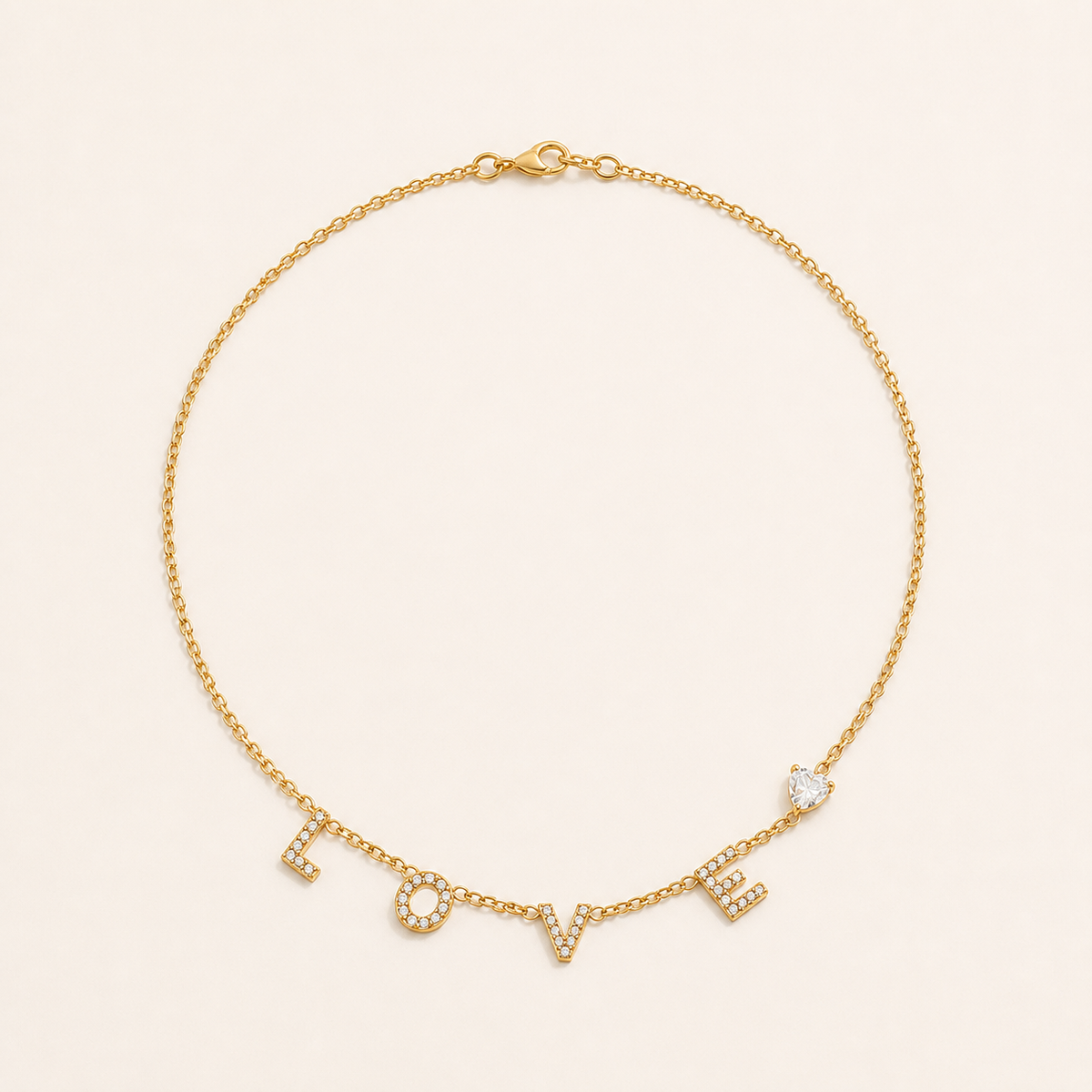 Gold LOVE letter zircon necklace on a warm cream background